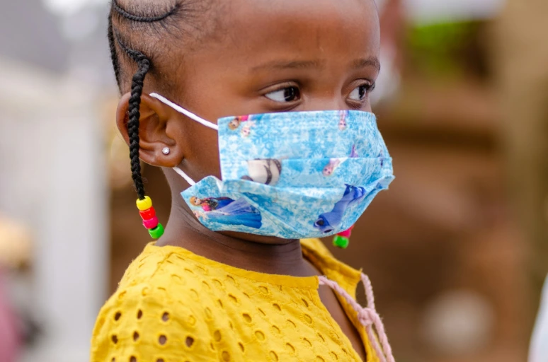 a little girl wearing a face mask and braids